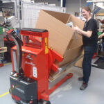 Rotator - Mitarbeiter entnimmt Material aus geneigter Pappbox